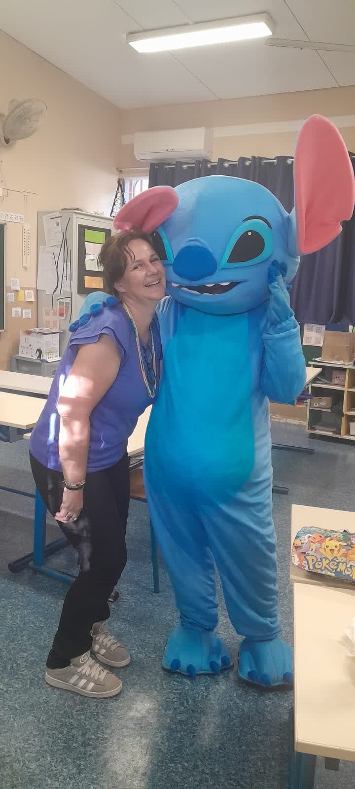 Mascotte géante bleue posant avec une invitée lors d'une animation enfants à La Réunion